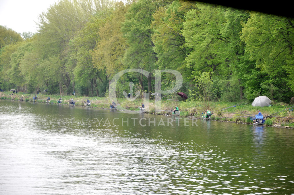 Über den Sacrow-Paretzer Kanal geht es weiter nach Paretz. Seit 1876 verbindet der Kanal den Jungfernsee mit der Havel unterhalb von Werder. Über diesen Kanal wird der weite Umweg über die Potsdamer Havel sowie die Engstelle am Caputher Gemünde von der Berufsschifffahrt umgangen. Wie unser Foto zeigt, ist der Kanal ein Eldorado für Angler. Wir folgen dem fast geraden Kanal, bis wir in der Nähe von Paretz sowohl die Mündung des Havelkanals als auch ein paar Meter später die Mündung der (Potsdamer) Havel erreichen.